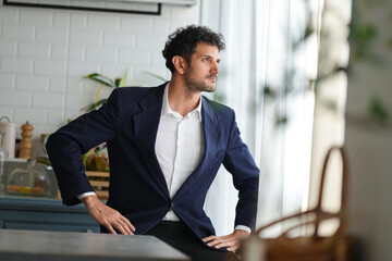 Young handsome businessman at the modern kitchen having vegan lunch, looking at his smartphone. Office worker having breakfast before working day at home