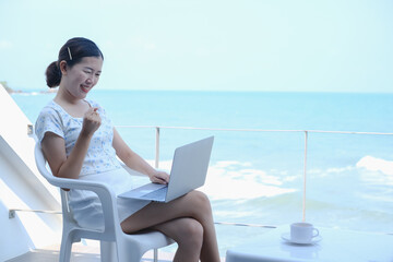 Young asia woman playing laptop computer on tropical beach