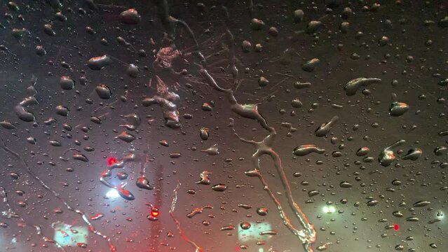 Rain drops on window windshield jaw drop in city at night travel