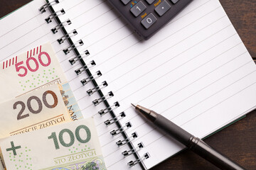 Polish currency notes, a calculator, and a pen on a notebook symbolizing the social assistance...