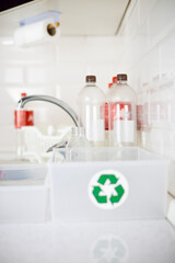 Plastic bottles stand in the kitchen against the backdrop of trash cans. Plastic bottles are washed and packed into boxes for recycling. The concept of environmental friendliness, plastic recycling.