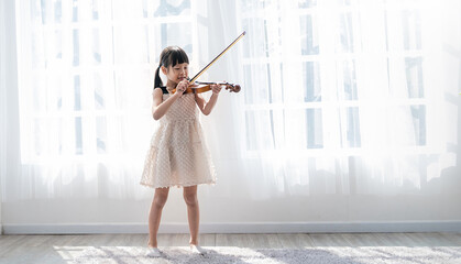 Portrait of young asian toddler little girl practice learning violin class room in white room at...