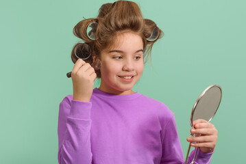 A young girl with her hair in rollers is looking at herself in a mirror