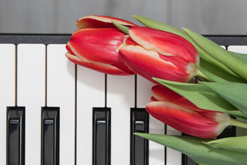 On a keyboard are three red tulips.