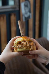 pulled pork hamburger in hand, photographed close up