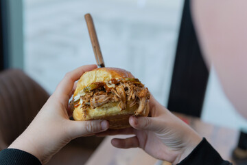 pulled pork hamburger in hand, photographed close up