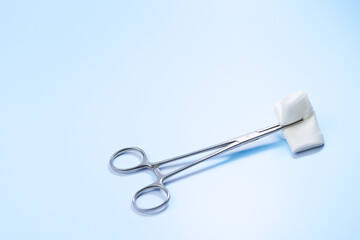 A pair of scissors with a white pad on top of it. The scissors are silver and have a sharp point. The white pad is soft and fluffy, and it looks like it could be used for cleaning or wiping
