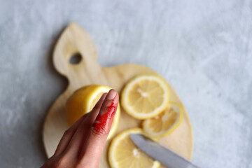 Injured finger close up photo. Bleeding female hand on grey background with space for text. 