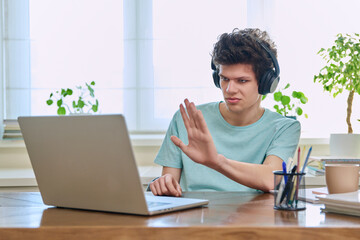 Guy student in headphones looking at web cam computer, talking studying online