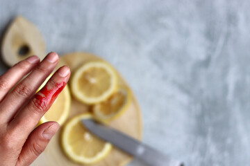 Woman accidentally cuts her finger. Real blood on woman's hand. Female hands cut lemons on a wooden...