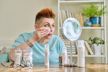 Middle-aged woman with a mirror taking care of her facial skin
