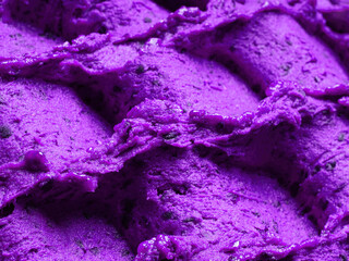 Frozen Lavender flavour gelato - full frame detail of sorbet. Close up of a violet surface texture of Ice cream filled with pieces of mixed flowers.