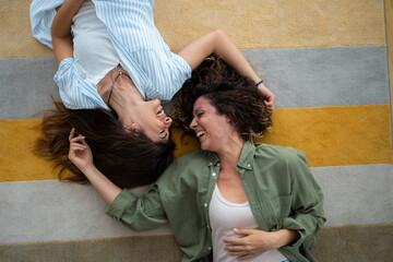 Photo of a beautiful joyful couple looking at each other while lying on the floor at home.