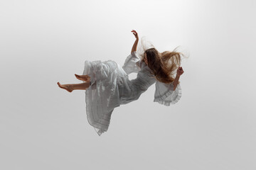 Woman dressed in flowing white gown suspend in mid-air, her long blonde hair cascading around her...