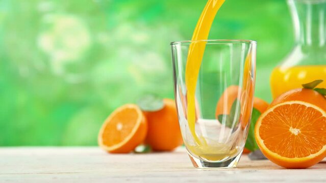 Super slow motion of pouring orange juice into glass. Placed on white table with kitchen interior. Filmed on high speed cinema camera, 1000 fps.