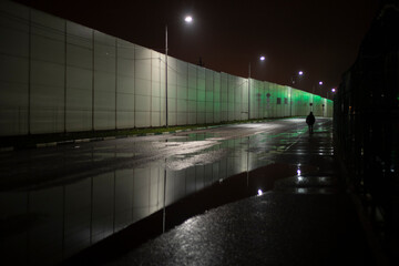 A man walks along the road at night. A man in the distance.