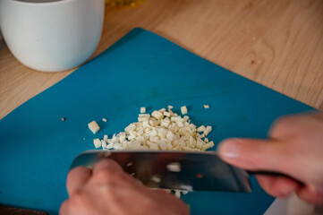 a man finely chops garlic on a plastic board