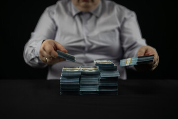 Front view. A businessman on a black background puts stacks of dollars from the firebox. A...