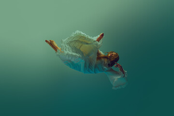 Young woman in dynamic pose, her vintage white dress fanning out beautifully during she falling...