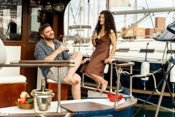Adult man and woman - Couple enjoying sparkling wine on yacht - sunset background, luxury leisure,...