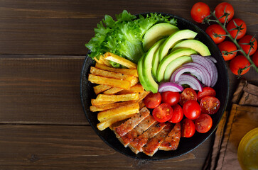 Grilled sliced pork steak with potatoes, tomatoes and avocados