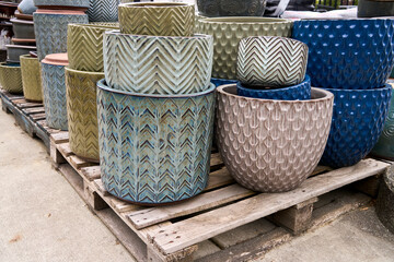 Many large colorful plant pots sitting on pallets for sale at a garden center.