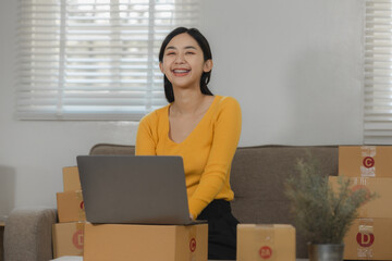 A beautiful female entrepreneur of an online small business is proudly working in her personal warehouse with boxes full of merchandise, Verify customer information before delivering the product