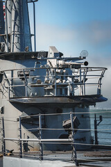 Close up view of naval ship superstructure with gun mount, radar dishes, and communication devices....