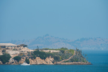 Scenic view of rocky island with structures, likely Alcatraz Island in San Francisco Bay. Calm...