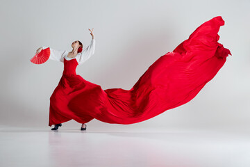 Female flamenco dancer in motion, elegant woman with red costume and fans performing flamenco dance...