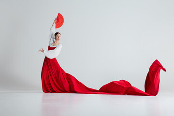 Female flamenco dancer in motion, elegant woman with red costume and fans performing flamenco dance...