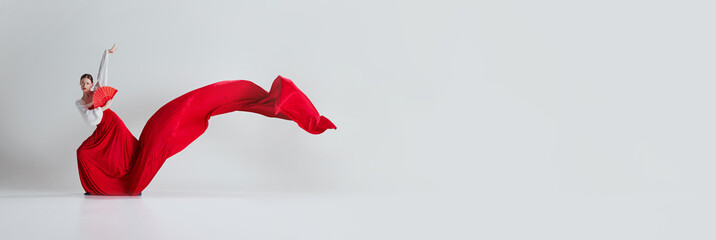 Capturing the spirit of flamenco. Female dancer with dramatic red skirt and fan showing passion and dramatic. Concept of art of movement, classical dance, beauty. Banner. Empty space to insert text © master1305