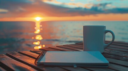 Fototapeta premium Coffee mug and notebook on wooden table,&nbsp;sea,&nbsp;sky and sunset in the background