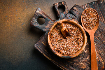 Wooden bowl with flax seeds, on a dark background. Organic food, superfood. Top view.