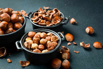 Shelled hazelnuts in a bowl on a dark background. Organic healthy autumn nuts. Close up.