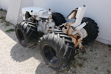 Small vintage tractor with wide tires, painted white, used for transportation in salt production factory, displayed as exhibit. 