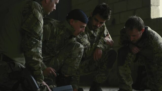 Soldiers kneeling around map and talking indoors