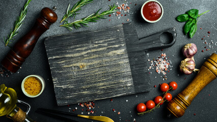 Wooden cutting board and spices, herb for food on black stone table. Menu, recipe mock up, banner...