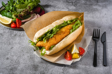 Fried fish sandwich with greens on the stone table. Turkish name Balik Ekmek