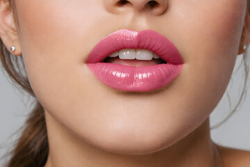 Fototapeta premium A beautiful woman's lips with pink lipstick. close up shot. glossy lips.
