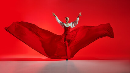 Passionate woman, flamenco dancer in stylish costume with skirt spreads like wings, performing...