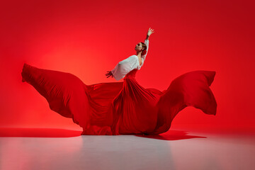 Passionate woman, flamenco dancer in stylish costume with skirt spreads like wings, performing...