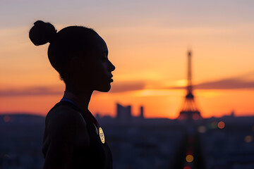 Fototapeta premium Dramatic silhouette of a gymnast with an Olympic medal hanging around their neck, standing before the Parisian skyline at dusk