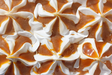 Vanilla ice cream poured with caramel. The sweet and cold dessert for refreshment during the summertime. Closeup view from above.