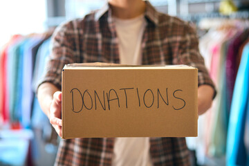 Close Up Of Male Charity Volunteer Holding Box Labelled Donations Towards Camera