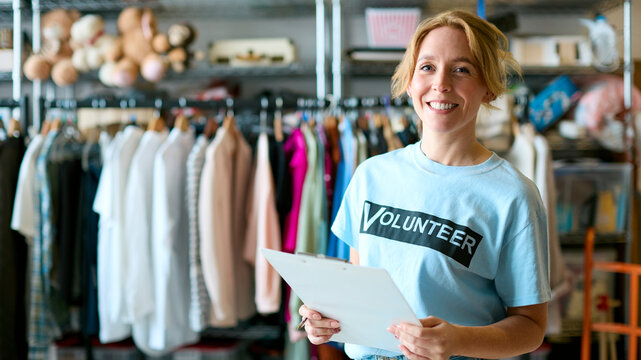 Portrait Of Female Charity Volunteer With Clipboard Working At Clothing Thrift Store