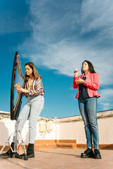 Modern harp and voice duo rehearsing on the roof of a building