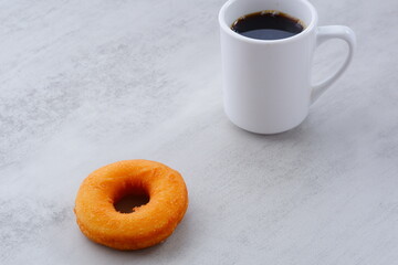 リング状のドーナツと、白いマグカップに入ったコーヒー
