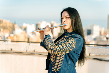 Young modern flutist girl playing cheerful