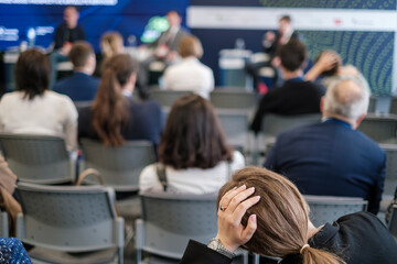 Focused image of a woman feeling stressed or overwhelmed while attending a business seminar. She...